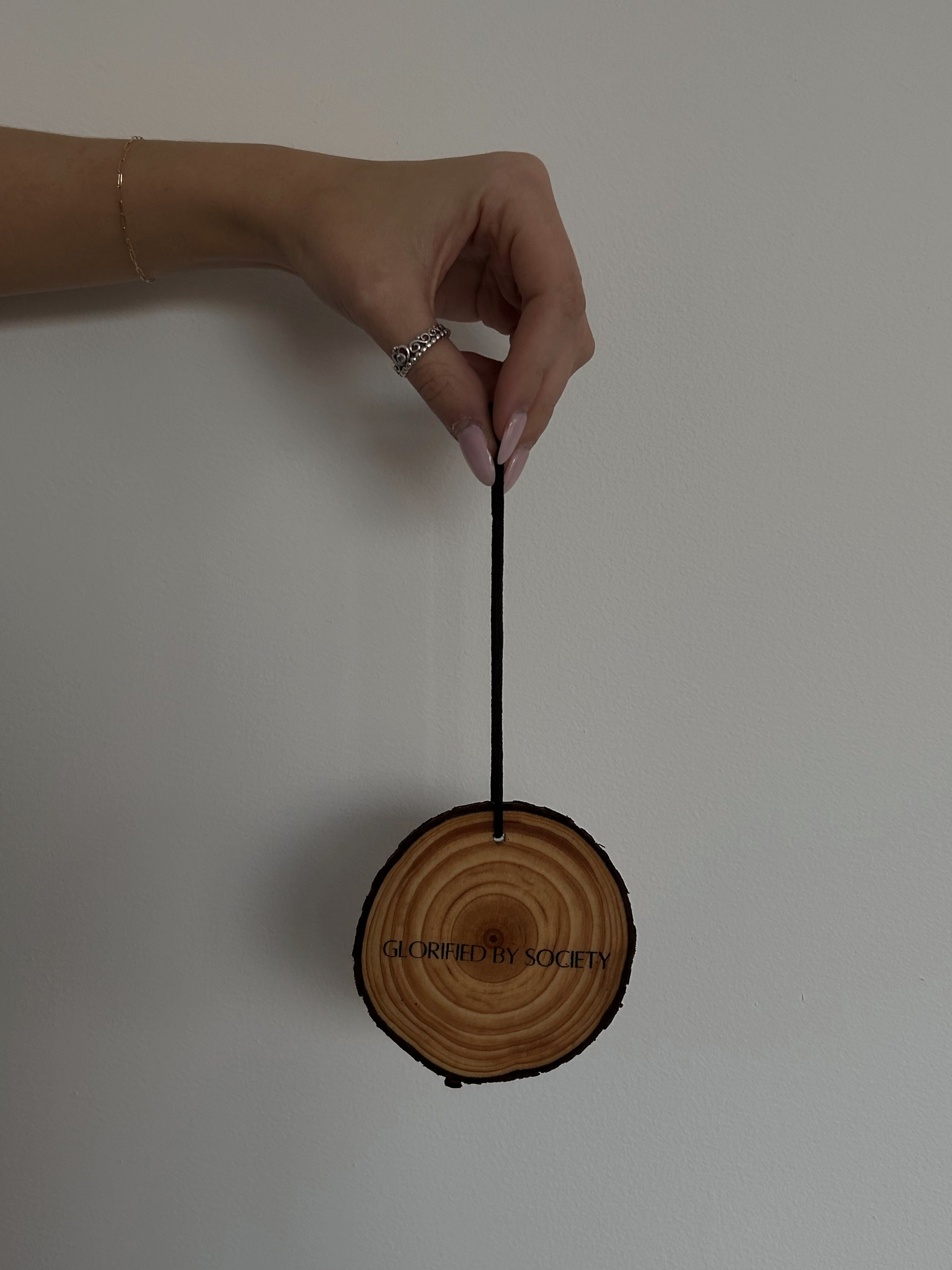 Glorified By Society luxury car fragrance diffuser, featuring a 3-inch elegant design with a black elastic cord for easy hanging on a rearview mirror. Made with premium phthalate-free and paraben-free fragrances, this long-lasting car air freshener brings a sophisticated and luxurious scent to your vehicle, enhancing your daily commute. Safe for you and your family, the diffuser is hand-made with attention to detail.