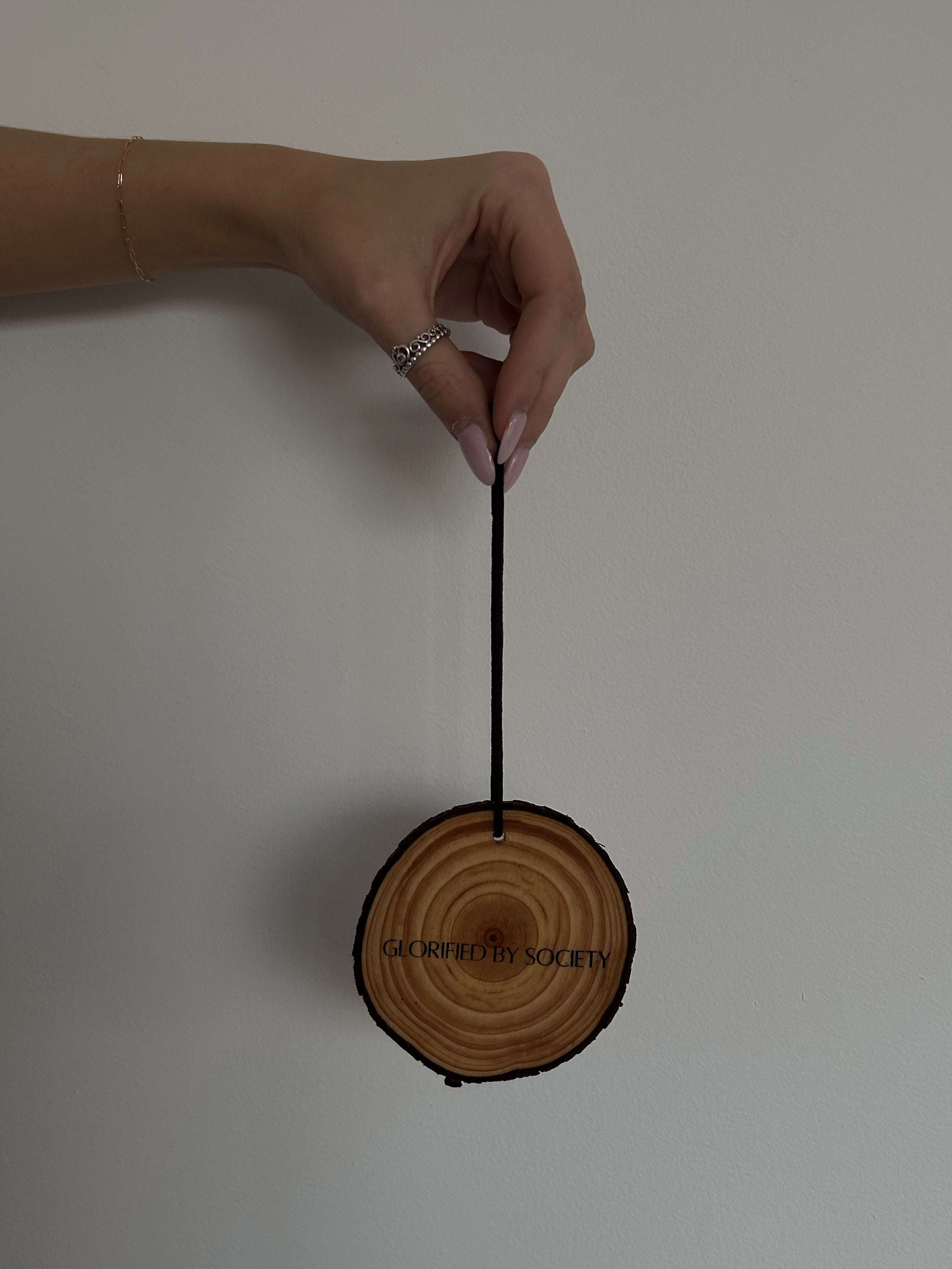 Glorified By Society luxury car fragrance diffuser, featuring a 3-inch elegant design with a black elastic cord for easy hanging on a rearview mirror. Made with premium phthalate-free and paraben-free fragrances, this long-lasting car air freshener brings a sophisticated and luxurious scent to your vehicle, enhancing your daily commute. Safe for you and your family, the diffuser is hand-made with attention to detail.